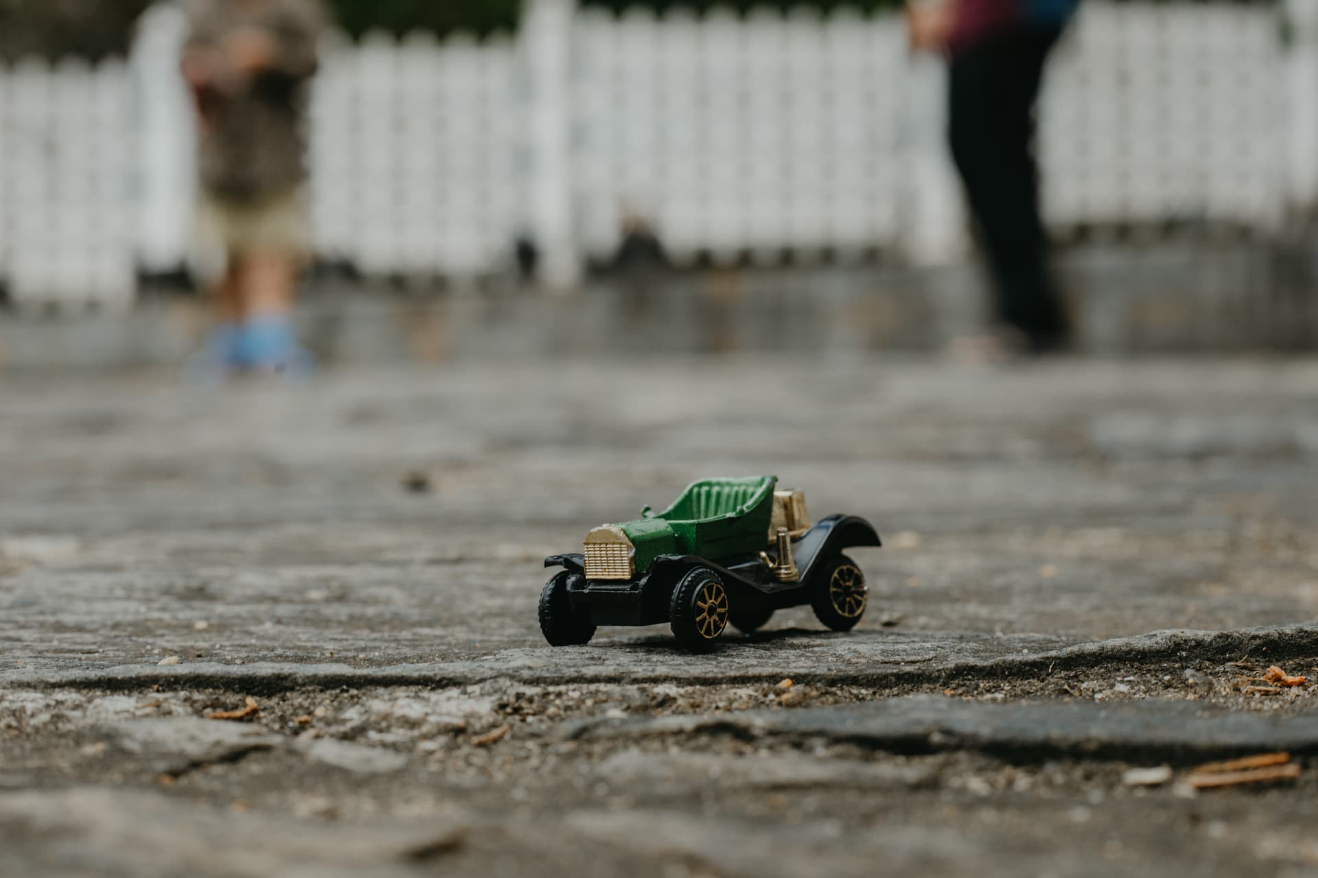 A small vintage toy car on a quiet stone path